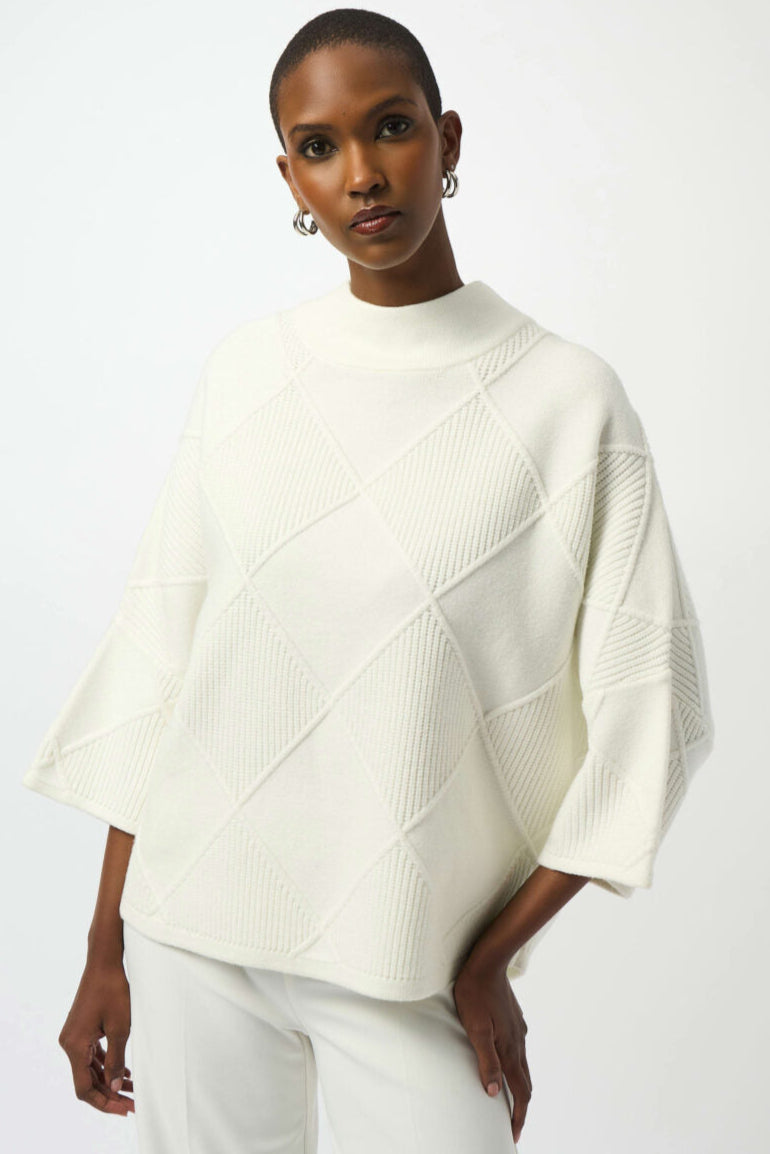 Woman wearing a white geometric-patterned sweater against a white background
