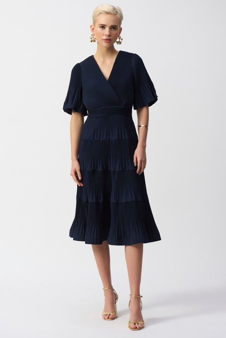 A model wearing a navy A-line midi dress with a V-neck and puff short sleeves.
