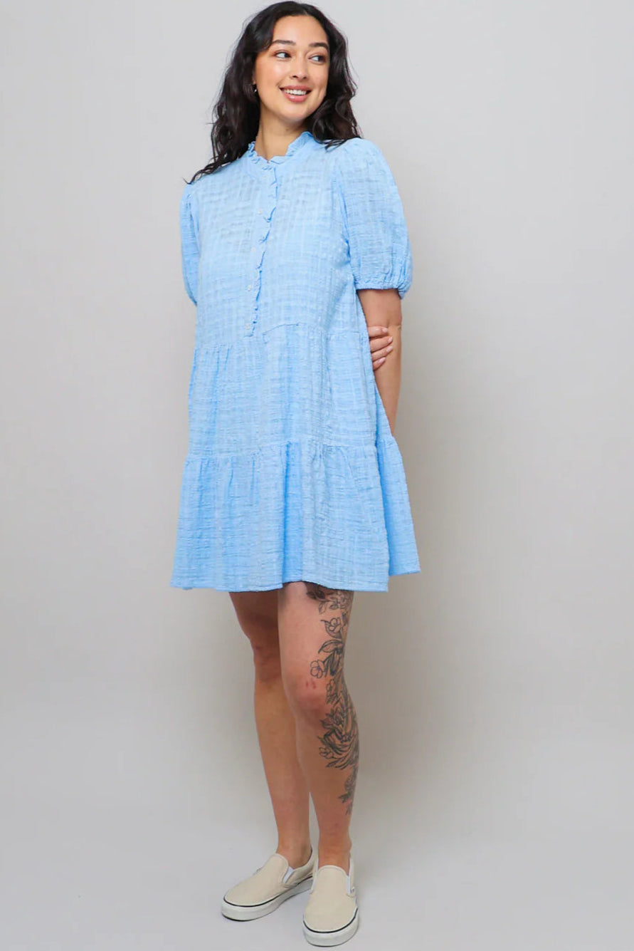 Woman wearing a light blue dress against a plain background