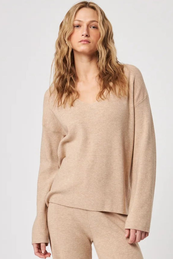 This camel-toned knit top offers understated elegance with its flattering V-neckline and relaxed, draped fit. Crafted from a soft, lightweight knit, it’s perfect for lounging in comfort or pairing with tailored pieces for a polished look. A versatile wardrobe staple that blends ease with sophistication.
