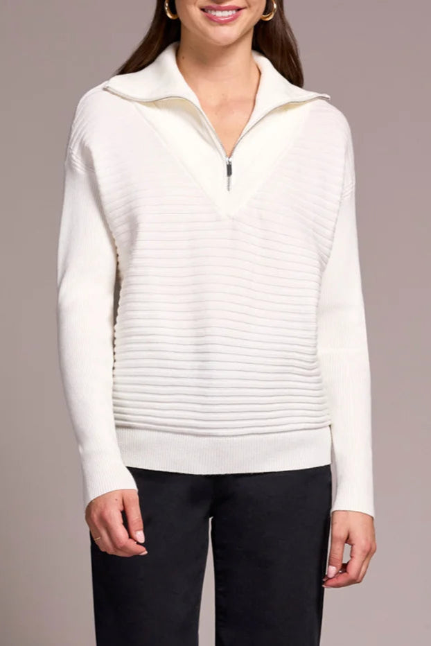 Person wearing a white sweater, black pants, and red shoes on a plain background