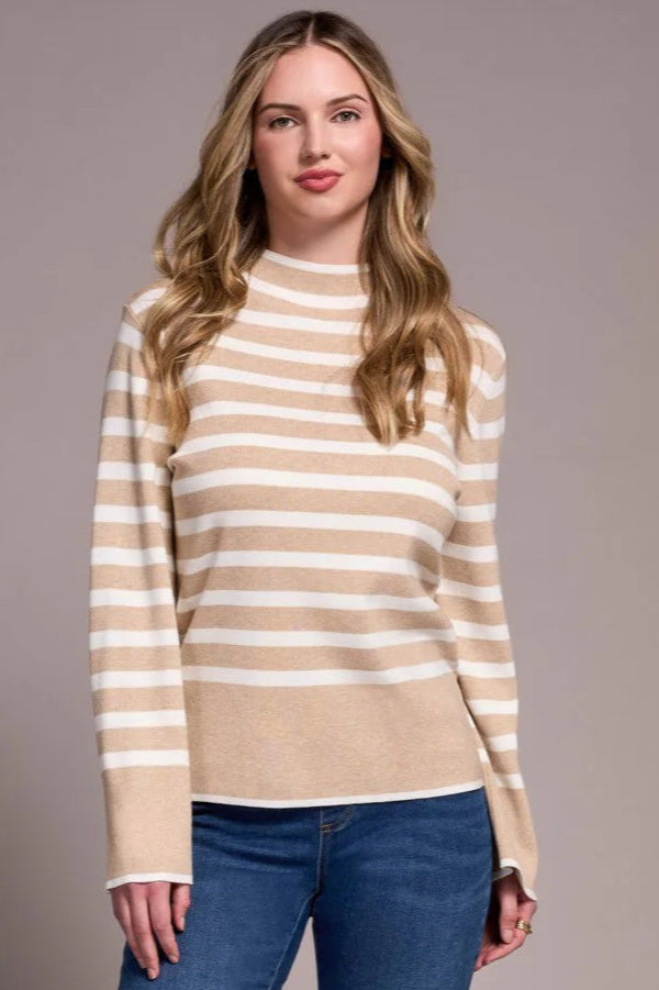 Woman wearing a striped sweater and blue jeans against a plain background