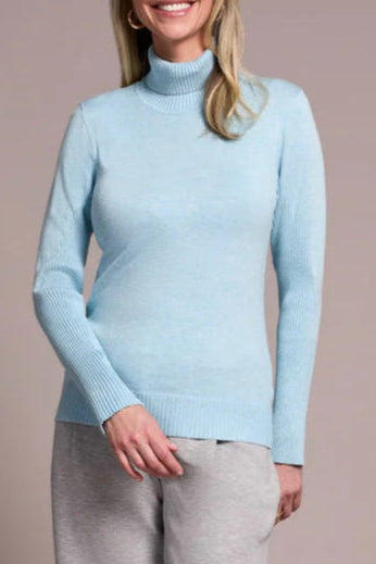Woman wearing a light blue sweater and gray pants against a beige background