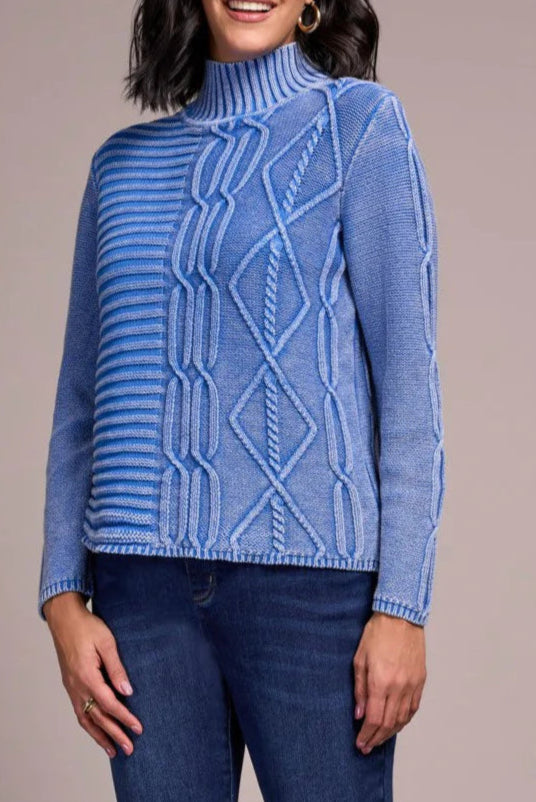 Woman wearing a blue sweater and jeans against a plain background
